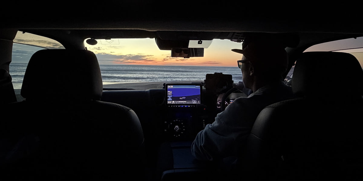 夜明け前、海へ向かう車内から見たフロントガラス越しの水平線。ダッシュボードの時刻は4時26分